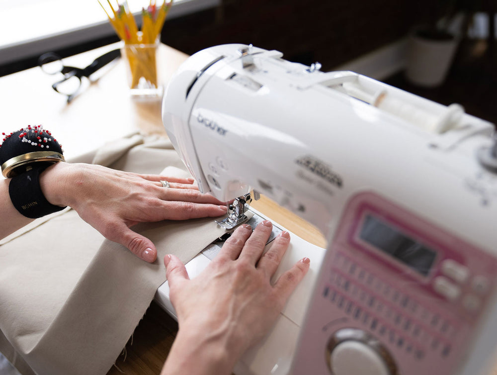 https://madestitch.co/cdn/shop/files/Sewing_classes_instructor_standing_in_front_of_table_with_a_sewing_machine_and_fabric.jpg?crop=center&height=754&v=1698770822&width=1000